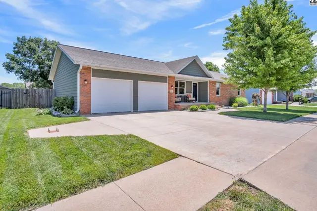 Exterior view of a ranch-style home with green siding, brick accents, and a two-car garage.