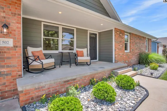 Inviting front porch with rocking chairs, brick and siding exterior, and manicured landscaping.