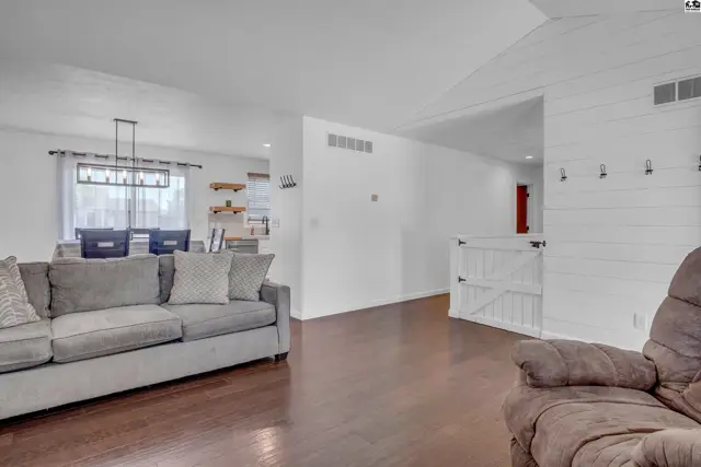 Spacious living room with gray sofa, dark wood floors, and white shiplap accent wall.