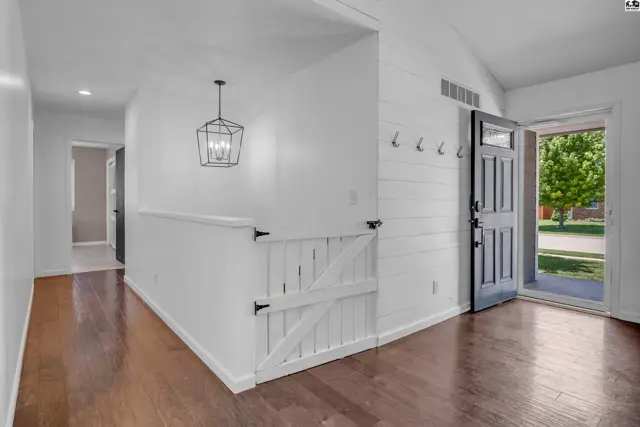 Entryway with dark wood floors, white shiplap walls, and a rustic barn-style gate.