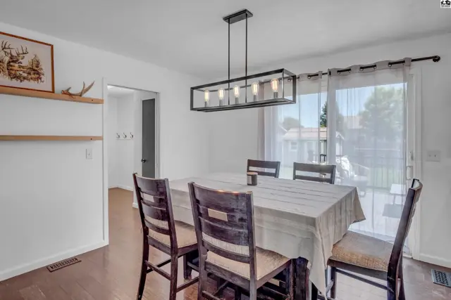 Dining room with dark wood table and chairs, a modern rectangular chandelier, and sliding glass doors to the patio.
