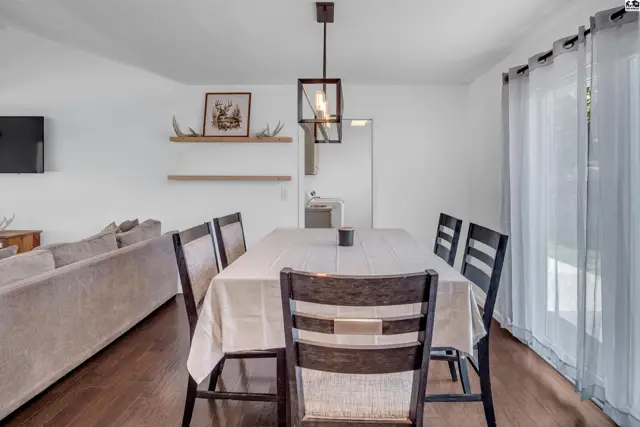Dining room with a large table, dark wood chairs, and a modern pendant light.