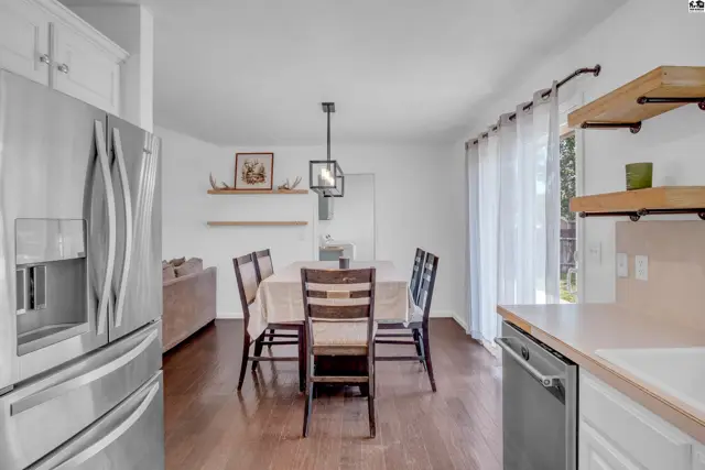 Dining area with dark wood floors, white walls, and stainless steel appliances.