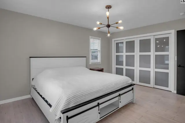 Modern bedroom with a white bed, gray walls, and frosted glass sliding closet doors.
