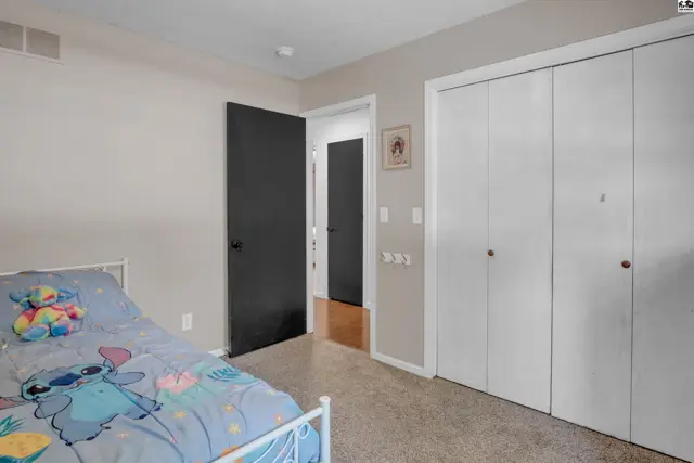 Bedroom with a twin bed, gray walls, and a large white closet with bi-fold doors.