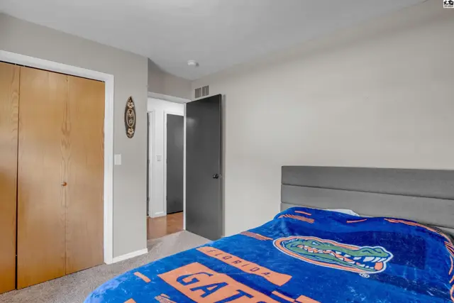 Bedroom with a large closet, gray headboard, and a blue blanket with an alligator logo.