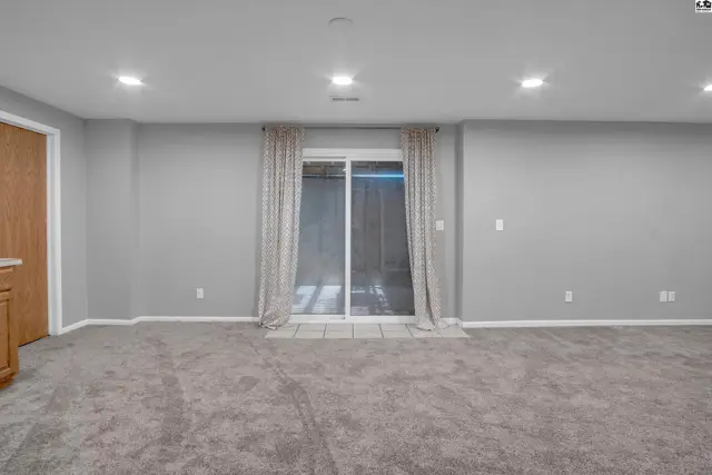 Spacious, neutral-toned living area with plush carpet and sliding glass doors.
