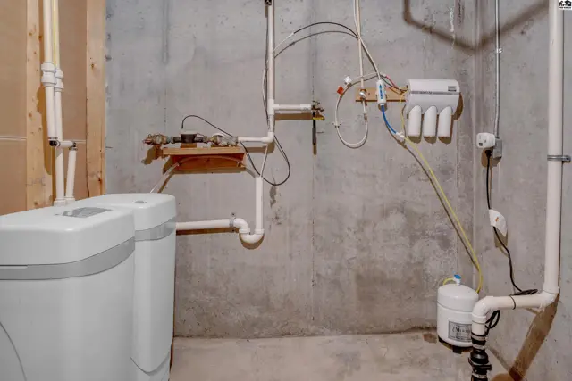 Basement utility area with two water softeners, a water filtration system, and concrete walls.