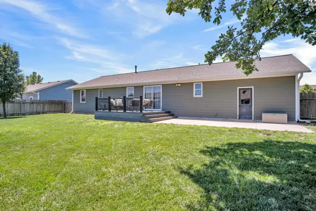 Spacious backyard with a large patio and a dark-railed deck accessible from sliding glass doors.