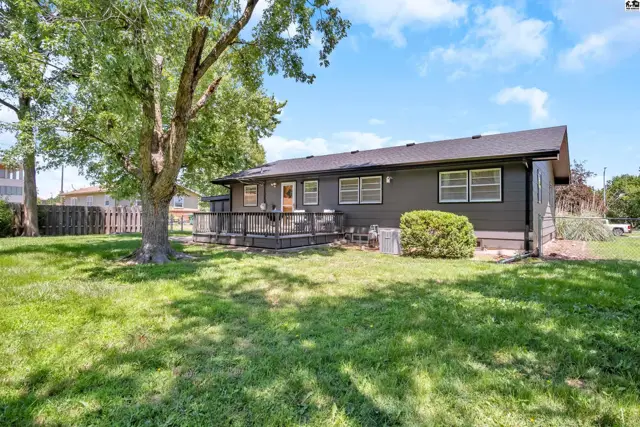 Dark gray siding and a large wooden deck highlight the rear exterior of this home.