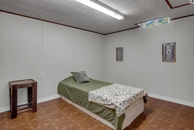 Minimalist bedroom with a single bed, patterned blanket, and a small wooden side table.