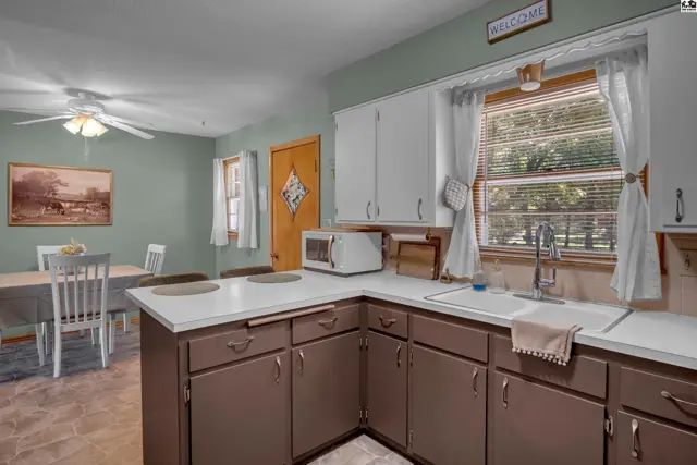 Kitchen with white countertops, dark brown cabinets, and a dining area with a table and chairs.