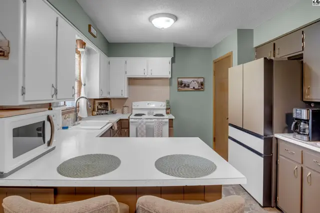 Spacious kitchen with white cabinets, white countertops, and stainless steel appliances.