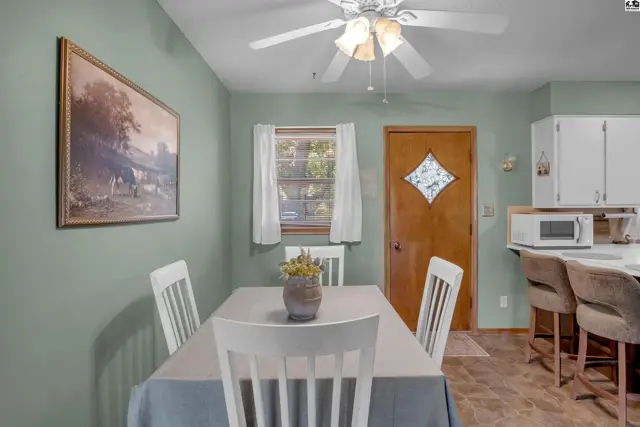 Dining area with a table, chairs, and a door leading to the kitchen with white cabinets.