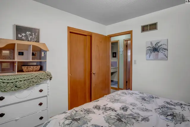 Bedroom with white dresser, wooden closet doors, and a view into a bathroom.