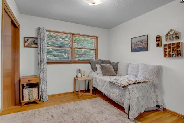 Cozy bedroom with a daybed, wood-framed window, and decorative wall shelves.