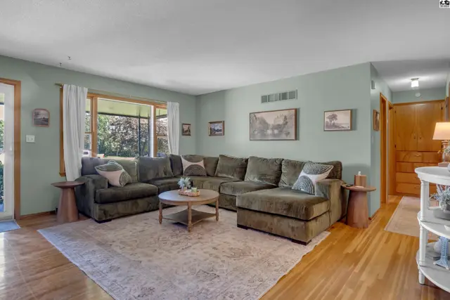 Spacious living room features a large sectional sofa, light wood floors, and a neutral rug.