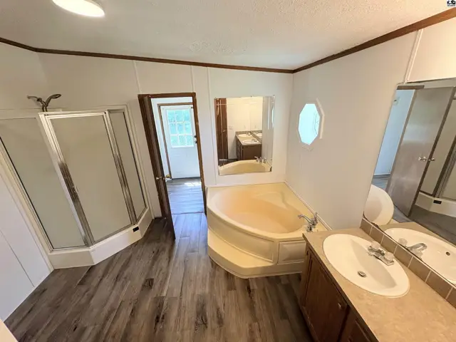 Spacious bathroom features a corner soaking tub, separate shower, and double vanity with wood cabinets.
