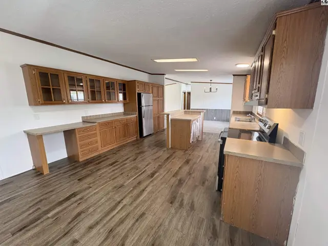 Spacious kitchen with light wood cabinets, stainless steel appliances, and wood-look flooring.