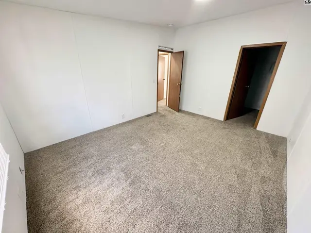 Spacious room with plush carpeting, white walls, and two interior doors.