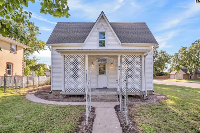 Charming white clapboard house with a decorative lattice porch and arched entryway.