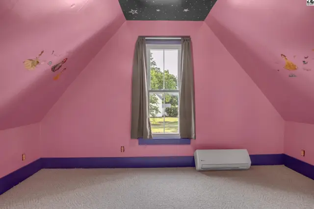 Attic bedroom with pink walls, starry ceiling, and carpeted floor.
