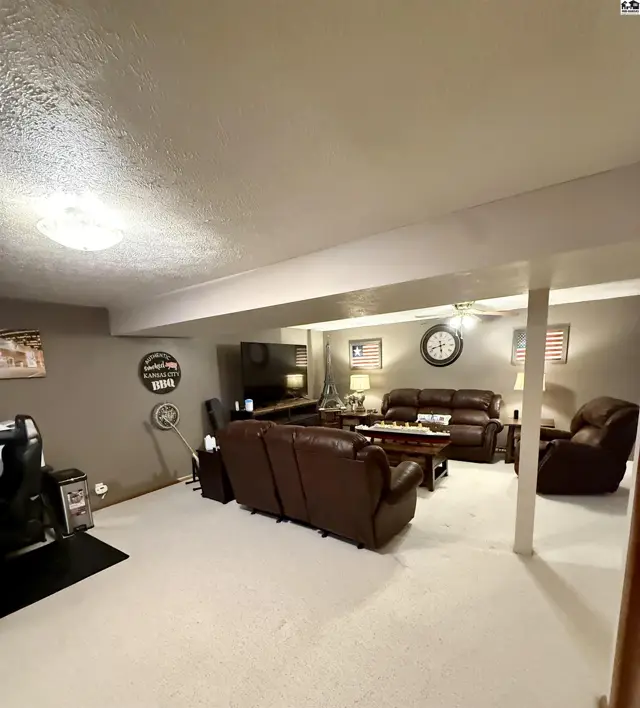 Spacious living room with plush brown leather furniture, a large TV, and decorative wall accents.