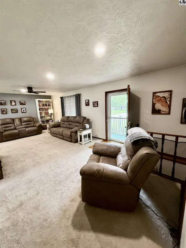 Spacious living room with plush brown recliners, a sofa, built-in bookshelves, and a door leading outside.
