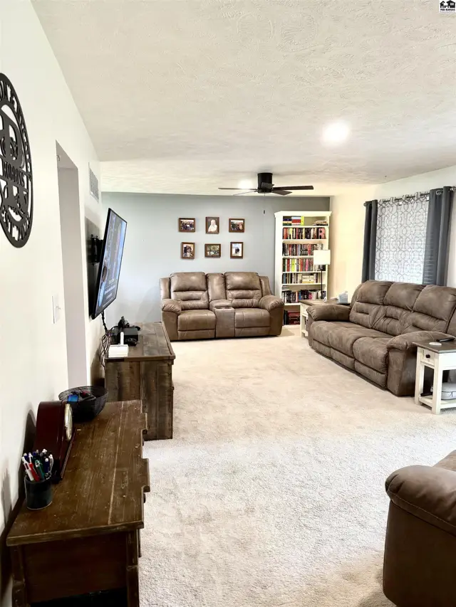 Spacious living room with plush carpet, comfortable recliners, and a built-in bookshelf.