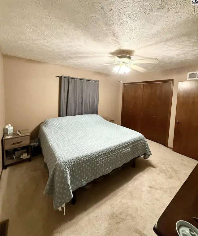 Spacious bedroom with a king-size bed, beige carpet, and wood-paneled closet doors.