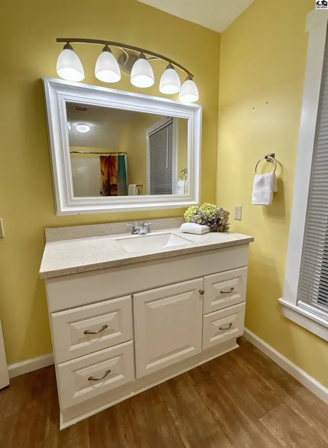 Bright bathroom with a white vanity, granite countertop, and yellow walls.