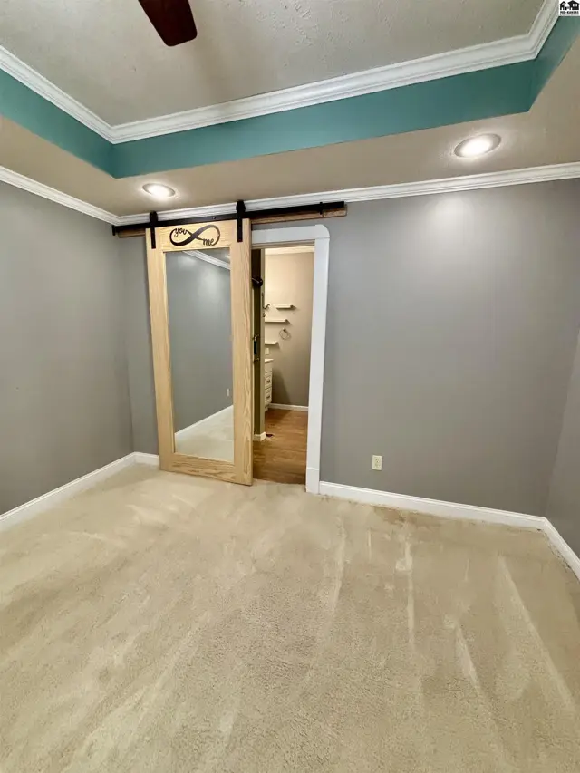 Bedroom with plush carpet, gray walls, and a unique sliding barn door with a full-length mirror.