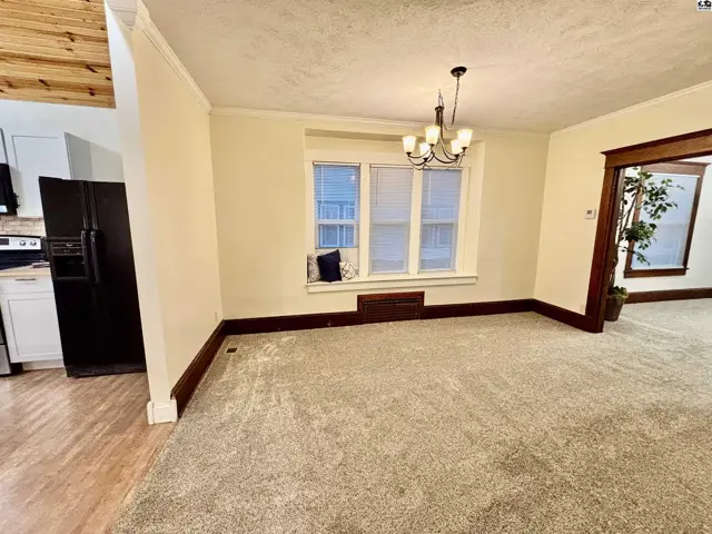 Spacious living area with plush carpet, dark wood trim, and a large window.