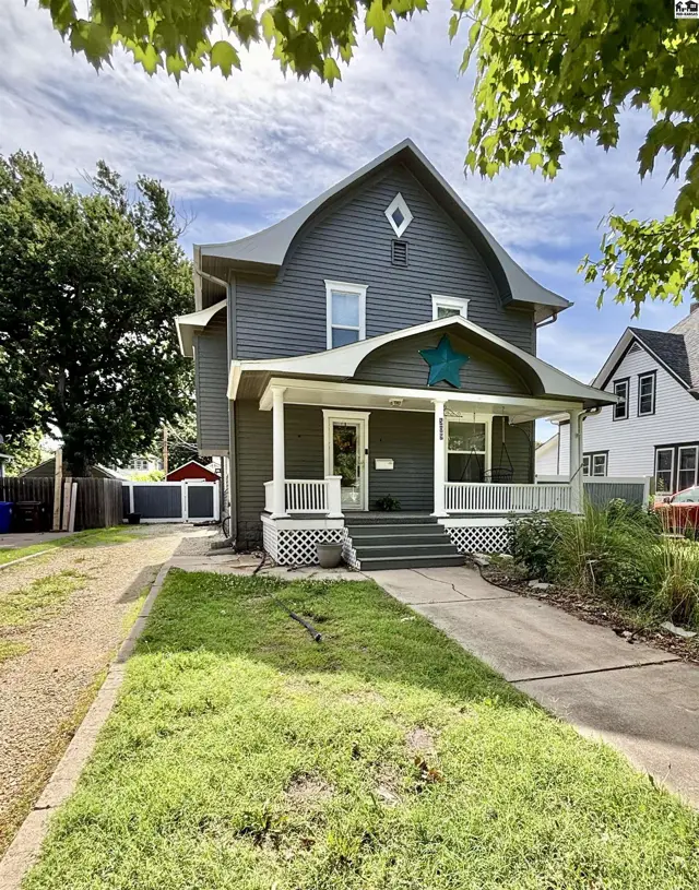 Dark gray siding and a welcoming porch adorn this charming two-story home with a distinctive star accent.