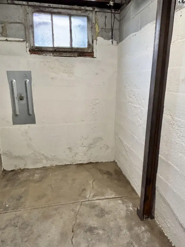 Concrete floor and block walls with a metal support beam and small window.