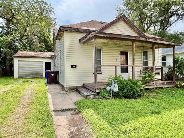 Exterior of a light-yellow house with a covered porch, wooden swing, and detached garage.