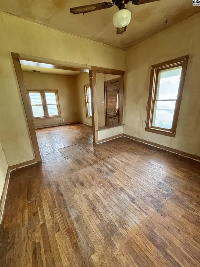 Living room with hardwood floors, textured walls, and natural light from windows.