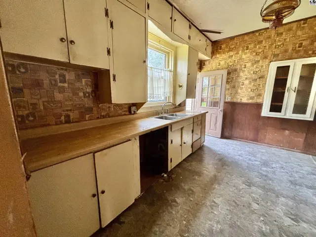 Vintage kitchen with cream cabinets, wood countertops, patterned backsplash, and a glass-front cabinet.