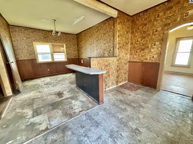 Retro dining area with patterned wallpaper, wood paneling, and a built-in counter.