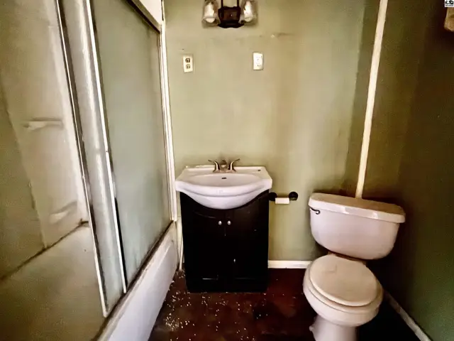 Small bathroom with a dark vanity, white toilet, and a shower stall with a glass door.
