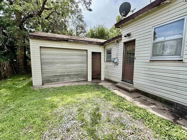 Exterior view of a detached garage with a roll-up door and a small adjacent door.
