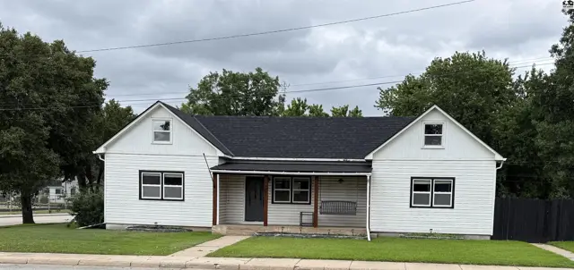 White vinyl-sided house with a dark shingle roof and a covered front porch.