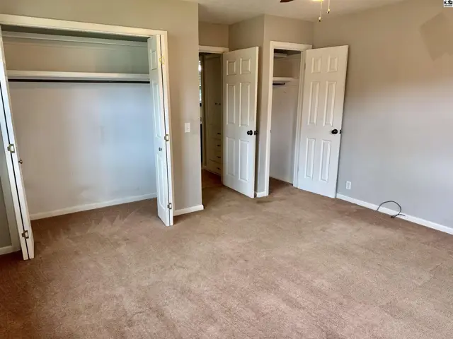 Spacious bedroom with plush carpet and two large white double-door closets.
