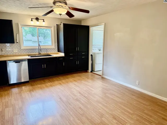 Modern kitchen with dark cabinets, stainless steel appliances, subway tile backsplash, and wood-look flooring.