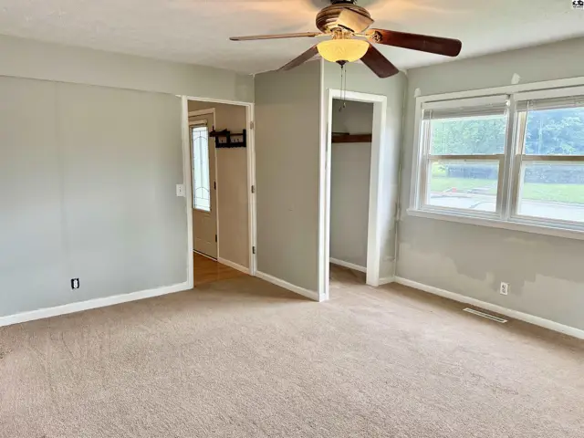 Spacious bedroom with neutral carpet, light gray walls, and a ceiling fan.