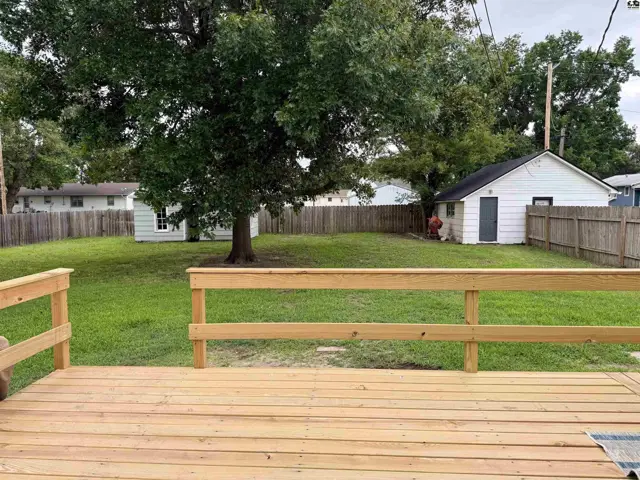 Spacious backyard with a new wooden deck, mature tree, and detached garage.