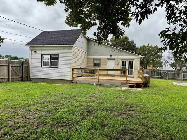 Backyard with a wooden deck and siding on a modest home.