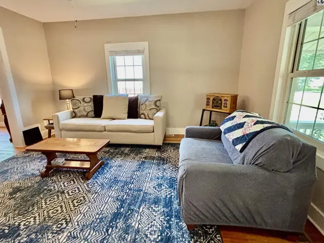 Cozy living room with neutral walls, two sofas, a wooden coffee table, and a patterned rug.