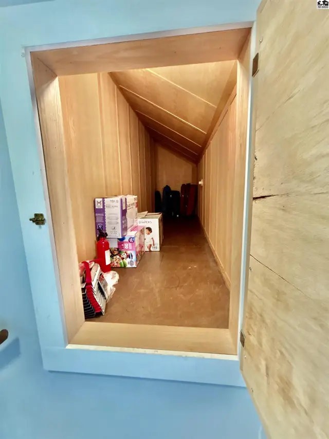 Sloped wooden ceiling and walls create a cozy, built-in storage nook filled with boxes.