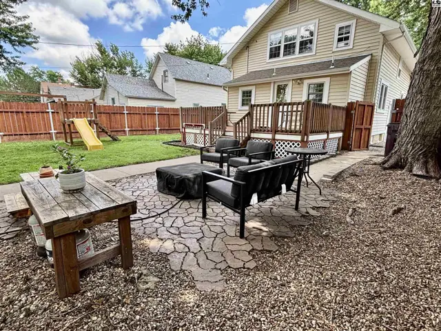 Spacious backyard with a wooden deck, patio furniture, and a playground.